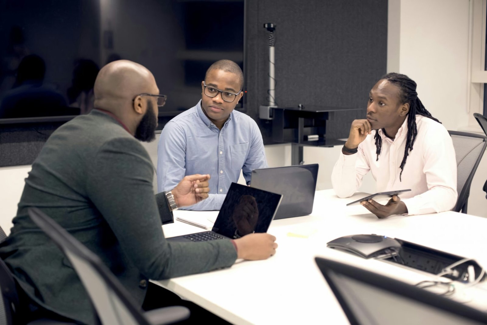 a group of people sitting around a table with laptops