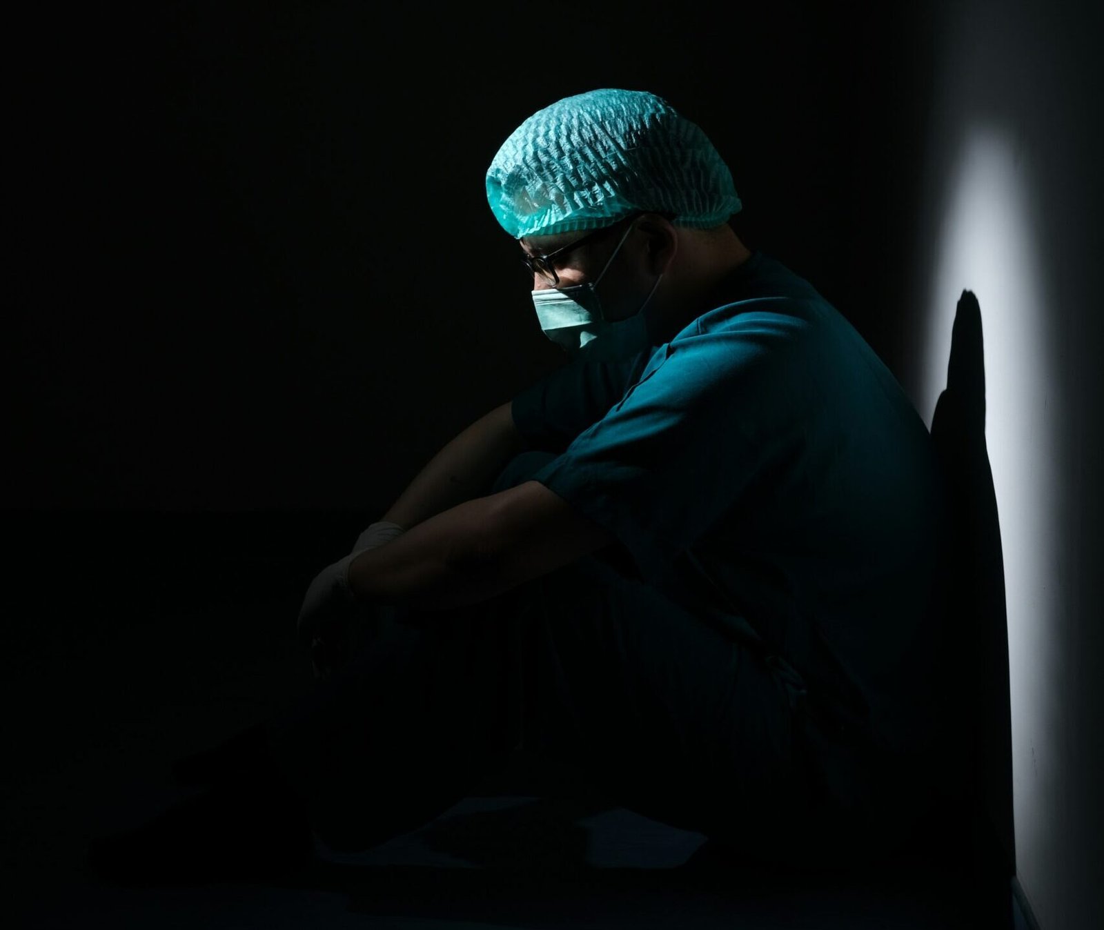 man in green shirt and blue knit cap sitting on floor